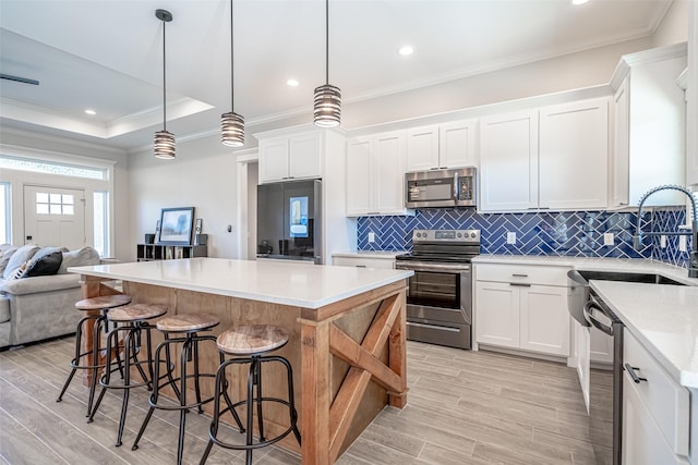 kitchen with white cabinetry, a kitchen island, decorative light fixtures, and appliances with stainless steel finishes