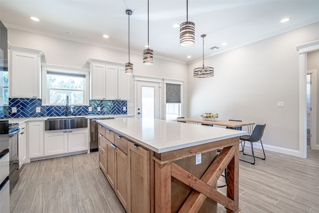 kitchen featuring sink, white cabinets, light hardwood / wood-style floors, a kitchen island, and hanging light fixtures