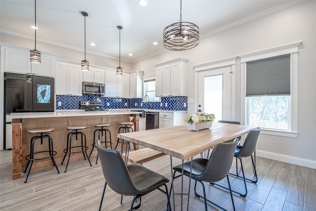 dining space with light wood-type flooring, plenty of natural light, and crown molding