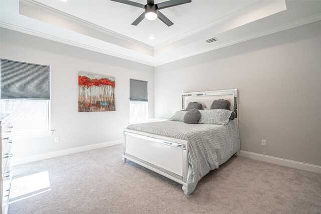 bedroom with ceiling fan, light carpet, and a tray ceiling