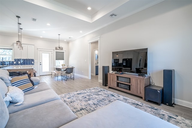 living room with crown molding, a wealth of natural light, and light hardwood / wood-style flooring