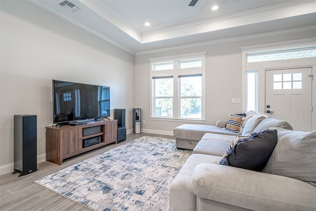 living room with light hardwood / wood-style floors, crown molding, ceiling fan, and a tray ceiling