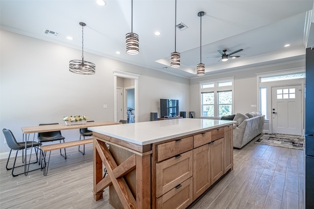 kitchen featuring ornamental molding, ceiling fan, light hardwood / wood-style flooring, a center island, and hanging light fixtures