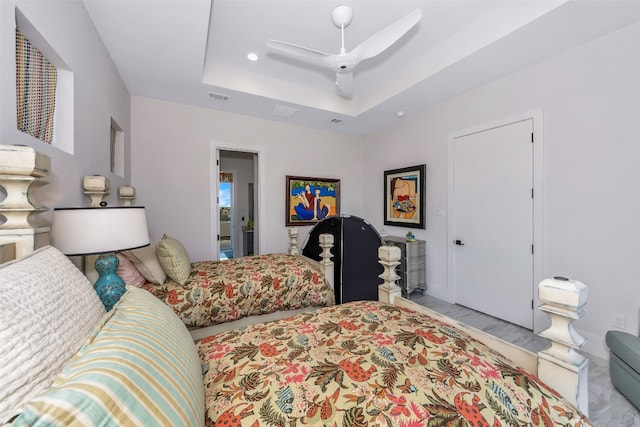 tiled bedroom with a tray ceiling and ceiling fan