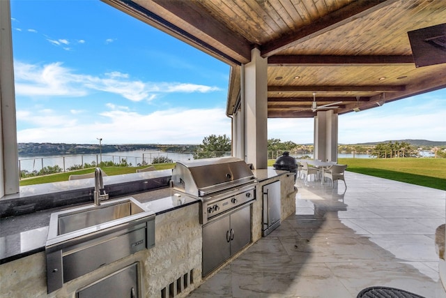 view of patio / terrace featuring area for grilling, a water view, and exterior kitchen