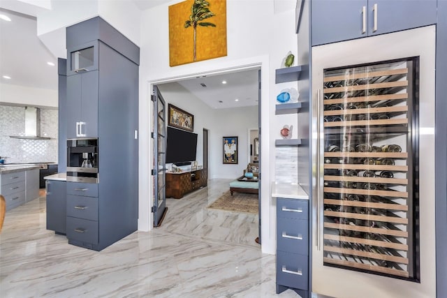 kitchen with light tile floors, stainless steel oven, wine cooler, wall chimney exhaust hood, and backsplash