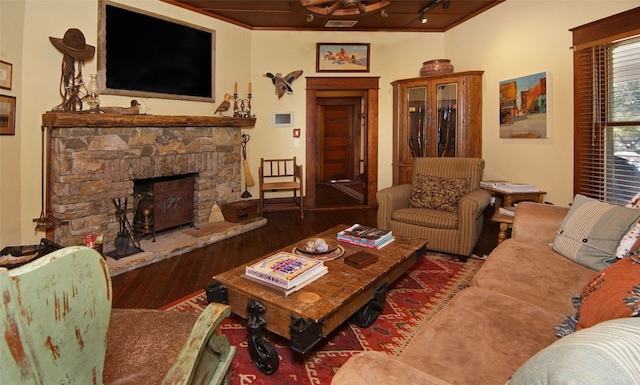 living room featuring a stone fireplace, dark hardwood / wood-style flooring, and ornamental molding