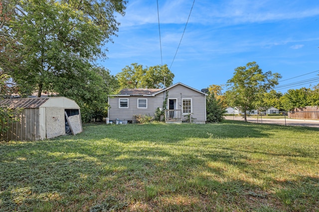 rear view of property with a storage shed and a yard