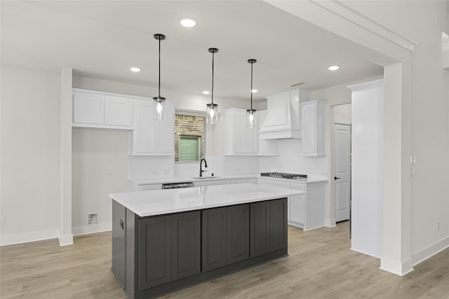 kitchen featuring white cabinets, a kitchen island, custom range hood, and light hardwood / wood-style flooring