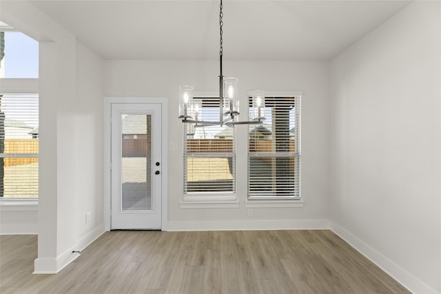 unfurnished dining area with a chandelier, light hardwood / wood-style flooring, and a wealth of natural light