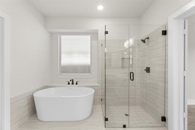 bathroom featuring shower with separate bathtub and tile floors