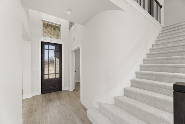 foyer entrance with a towering ceiling and light wood-type flooring