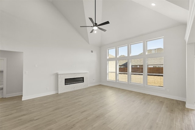 unfurnished living room featuring high vaulted ceiling, light hardwood / wood-style floors, and ceiling fan