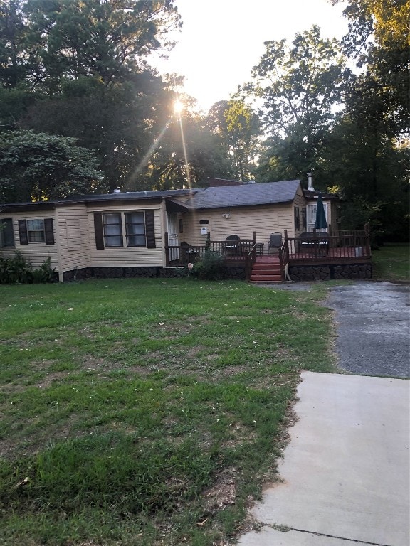 rear view of property with a wooden deck and a lawn