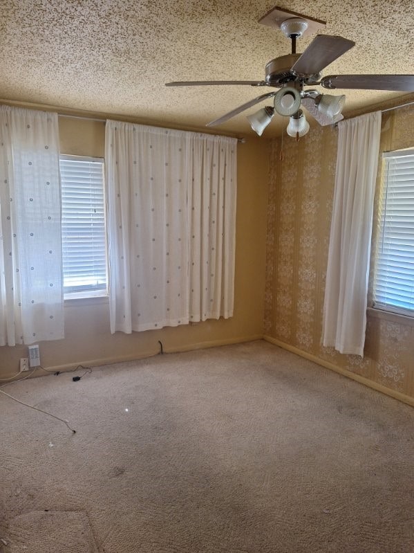 carpeted spare room featuring ceiling fan and a textured ceiling