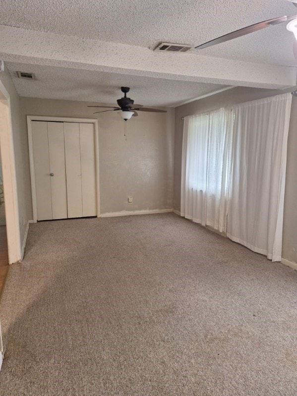 unfurnished bedroom featuring carpet flooring, ceiling fan, and a textured ceiling