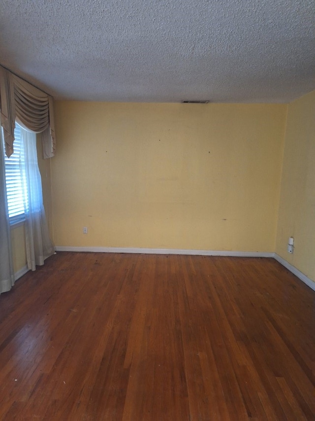 unfurnished room featuring dark hardwood / wood-style floors and a textured ceiling