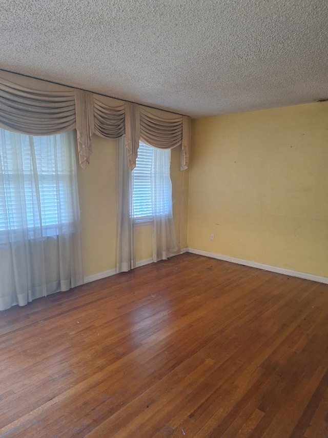 empty room with hardwood / wood-style flooring and a textured ceiling