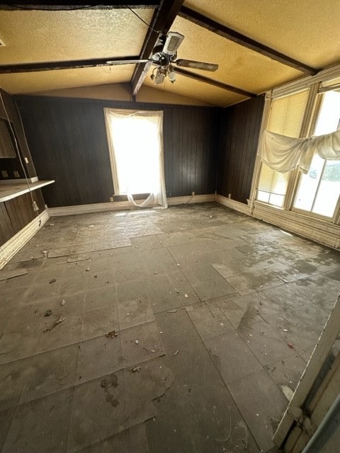 empty room featuring ceiling fan, lofted ceiling, and a wealth of natural light