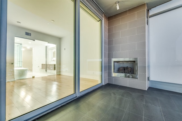 doorway to outside featuring a tiled fireplace and dark tile floors