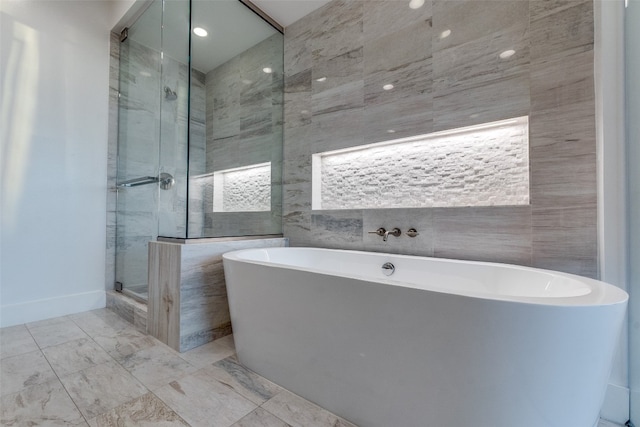 bathroom featuring tile walls, shower with separate bathtub, and tile floors