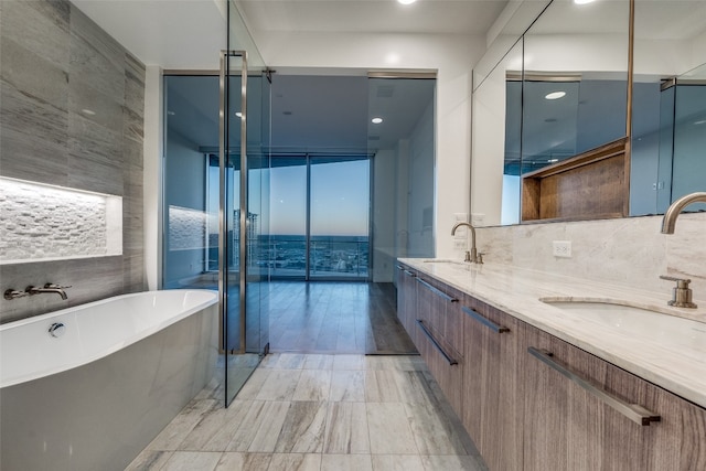 bathroom with tile walls, tile floors, dual vanity, a bathing tub, and tasteful backsplash