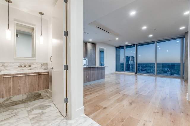 bathroom with backsplash, floor to ceiling windows, hardwood / wood-style flooring, and vanity