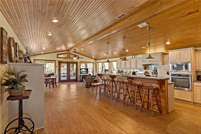 kitchen with appliances with stainless steel finishes, hanging light fixtures, wooden ceiling, light wood-type flooring, and a breakfast bar