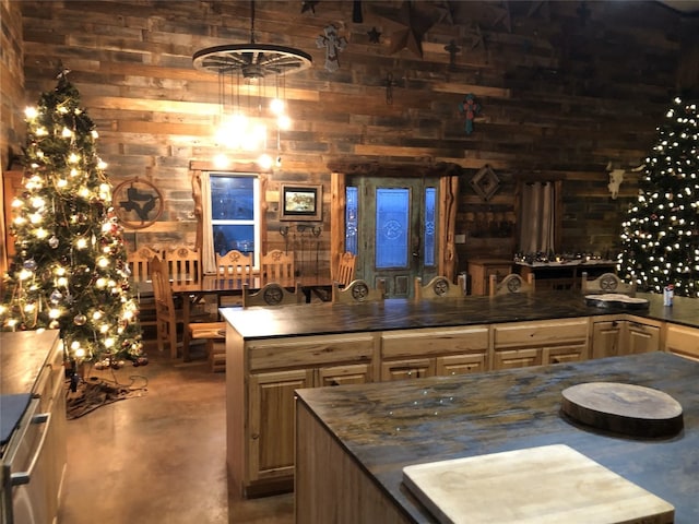 kitchen with a high ceiling, wooden walls, hanging light fixtures, and a kitchen island