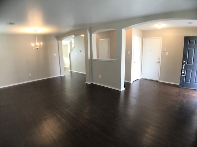 unfurnished living room with a notable chandelier and dark wood-type flooring