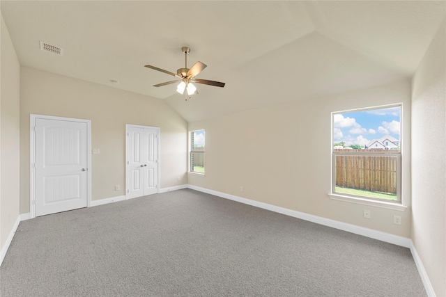 carpeted empty room featuring ceiling fan, a healthy amount of sunlight, and vaulted ceiling