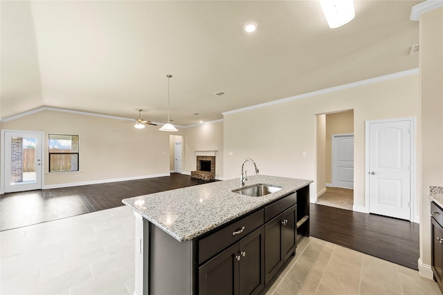 kitchen featuring vaulted ceiling, sink, light hardwood / wood-style floors, and a center island with sink