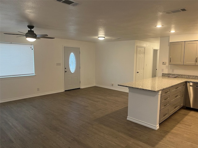 kitchen featuring dark wood-type flooring, light stone countertops, a textured ceiling, stainless steel dishwasher, and kitchen peninsula