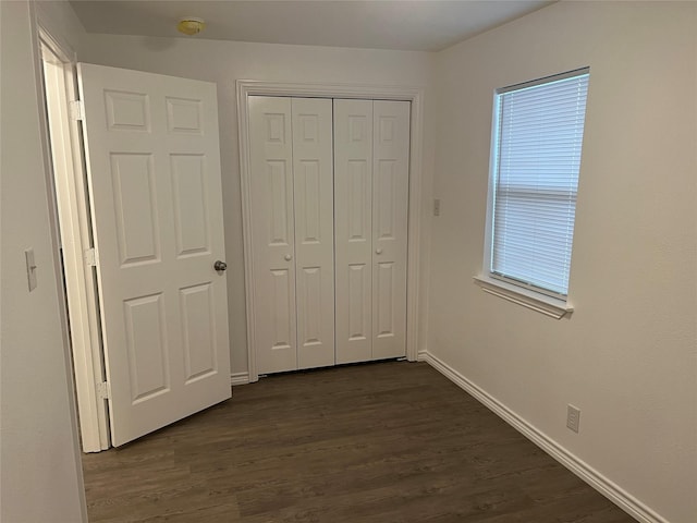 unfurnished bedroom with dark hardwood / wood-style flooring and a closet