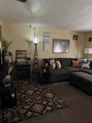 carpeted living room with a textured ceiling and a fireplace