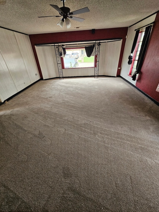 unfurnished bedroom featuring a textured ceiling, ceiling fan, and carpet