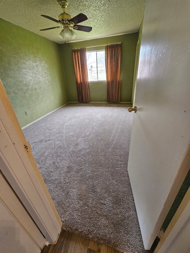 carpeted empty room with ceiling fan and a textured ceiling