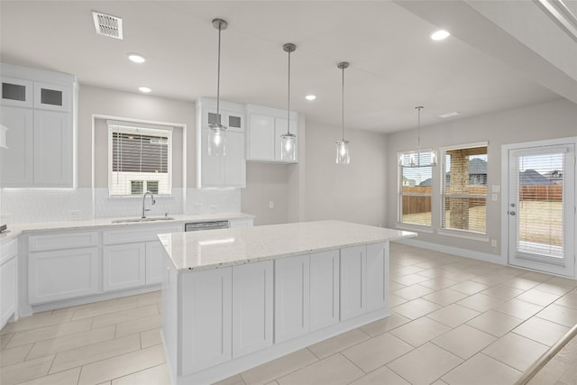 kitchen with a kitchen island, tasteful backsplash, white cabinets, hanging light fixtures, and sink