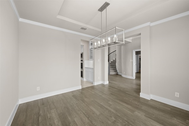 spare room featuring an inviting chandelier, a raised ceiling, and dark hardwood / wood-style flooring