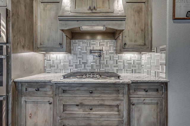 kitchen featuring appliances with stainless steel finishes, light stone countertops, extractor fan, and tasteful backsplash