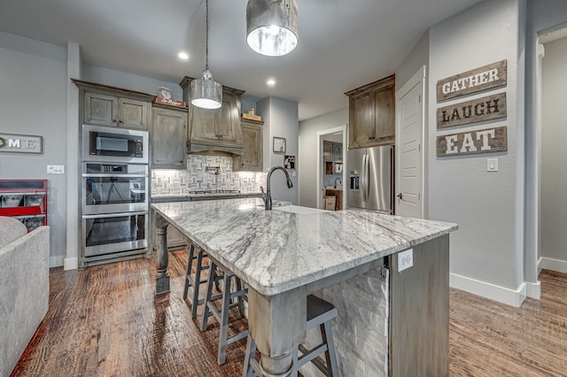 kitchen featuring hanging light fixtures, a large island with sink, sink, appliances with stainless steel finishes, and a breakfast bar area