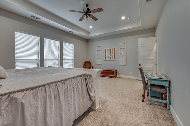 bedroom with ceiling fan, a raised ceiling, and light colored carpet