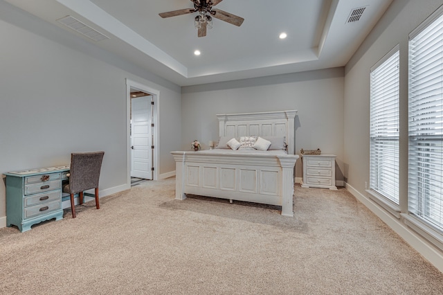 bedroom with a raised ceiling, light carpet, and ceiling fan