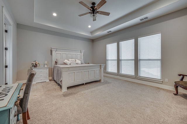 carpeted bedroom featuring a raised ceiling and ceiling fan