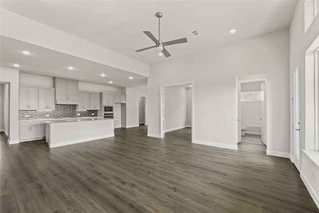 kitchen featuring dark wood-type flooring, an island with sink, stainless steel appliances, ceiling fan, and a wealth of natural light