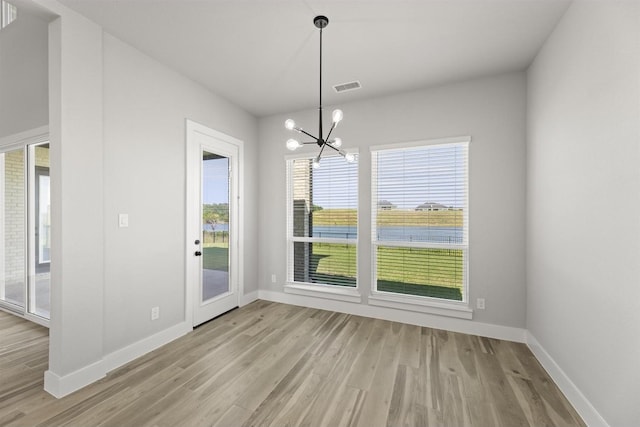 unfurnished dining area with light hardwood / wood-style flooring and a notable chandelier