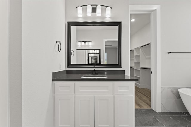 bathroom featuring vanity, a bath, tile patterned floors, and tile walls