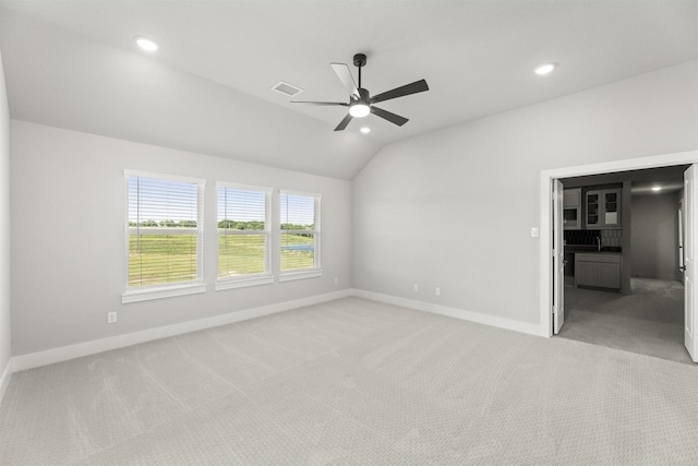 carpeted empty room with ceiling fan and vaulted ceiling