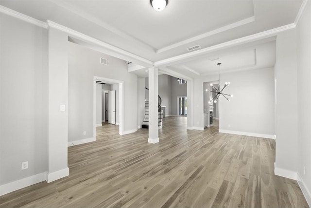 unfurnished living room featuring hardwood / wood-style flooring, ornamental molding, an inviting chandelier, and a tray ceiling