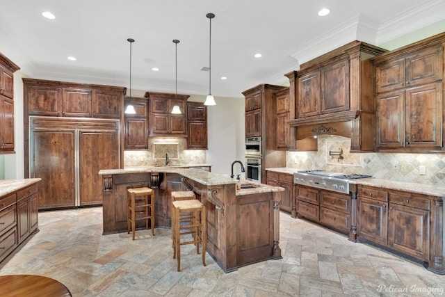 kitchen featuring backsplash, a center island with sink, stainless steel appliances, and decorative light fixtures